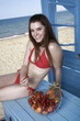 Photo: Female young adult with bowl of fruit on beach Female young adult with bowl of fruit on beach