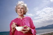 Photo: Female senior eating yogurt and fruit on the beach Female senior eating yogurt and fruit on the beach
