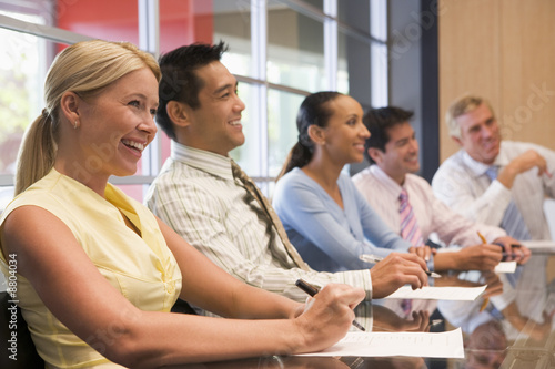 Photo: Five businesspeople at boardroom table smiling Five businesspeople at boardroom table smiling