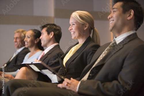 Photo: Five businesspeople smiling in presentation room with clipboards Five businesspeople smiling in presentation room with clipboards