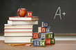 Pile of books with wooden blocks in front of chalkboard