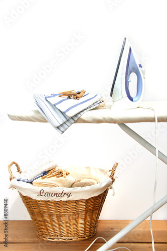 Ironing board with laundry against white background