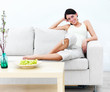 Foto: Smiling modern Happy young woman sitting on sofa Smiling modern Happy young woman sitting on sofa