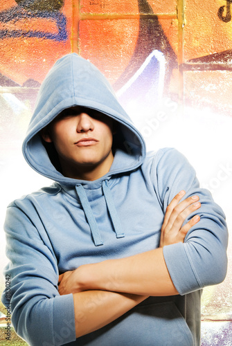 Photo: Cool looking man in a hood over abstract graffity background Cool looking man in a hood over abstract graffity background
