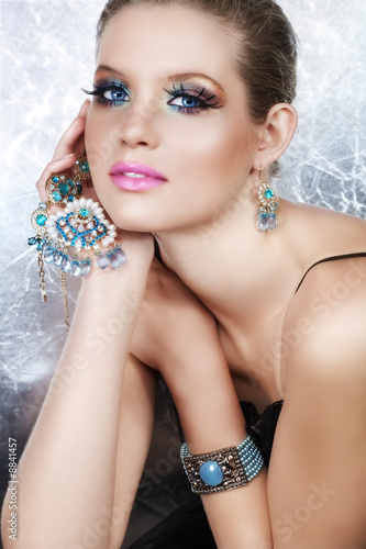 Blond woman with long false lashes holding pearl necklace