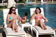 Two young girls with cocktails near the swimming pool