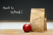 Paper lunch bag on desk with apple Paper lunch bag on desk with apple