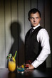 Barkeeper with wall background standing behind cocktails.
