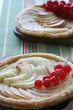 Two french apple tarts are served with red currant on the table