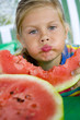 Little blond girl with a piece of watermelon in her hands