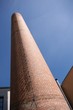 Alter, stillgelegter Fabrikschornstein ragt in den blauen Himmel