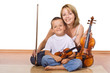 Woman and little boy sitting on the floor with violins