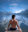 A man is sitting at the water where the blue sky is mirrored
