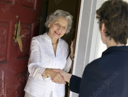 Photo: Smiling senior woman greeting visitor at the front door Smiling senior woman greeting visitor at the front door