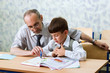 Teacher and schoolboy read alphabet. Primary school.