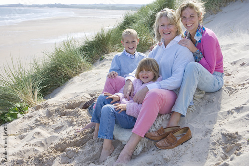 Photo: Multi-generation family sitting on beach Multi-generation family sitting on beach