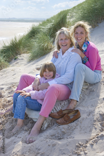 Photo: Multi-generation family sitting on beach Multi-generation family sitting on beach