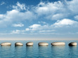 A row of stones in water. A pebble on a background of the sky A row of stones in water. A pebble on a background of the sky