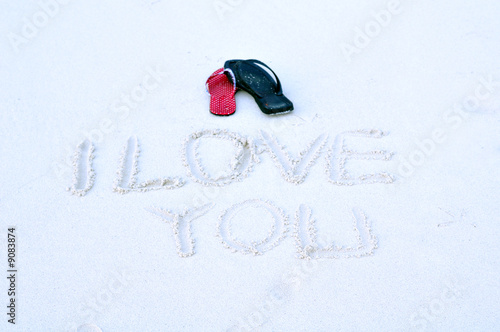 Photo: his and her thongs on a sandy beach his and her thongs on a sandy beach