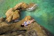 The woman relax on a stone among green waters