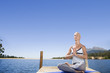 Woman meditating on lake dock