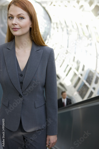 Foto: Businesswoman riding escalator Businesswoman riding escalator