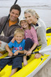 Young family sitting in kayak on beach