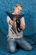 A young guitar player on a blue background holding the guitar