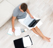 Busy young man sitting on floor and using a laptop