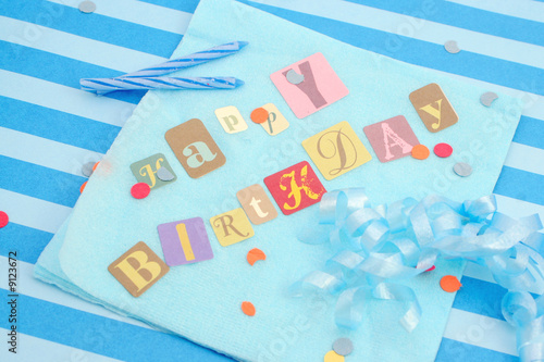 Photo: Happy birthday cut out letters on blue napkin Happy birthday cut out letters on blue napkin