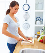 Smiling girl standing and cutting apple in the kitchen