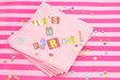 cut out letters spelling it's a party on pink napkins
