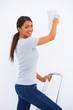 Portrait of a beautiful happy girl painting a white wall