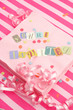 cut out letters spelling you're invited on pink napkins
