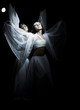 Two girls in white raiment dancing in semidarkness