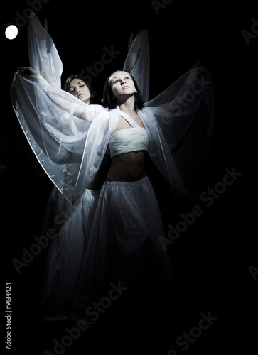 Photo: Two girls in white raiment dancing in semidarkness Two girls in white raiment dancing in semidarkness