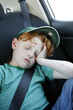 Young boy sleeping in the car, wearing his seatbelt.