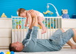 Father lying on back and lifting baby boy ( 1 year old ) at home