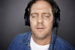 Man Wears Headphones Enjoys Music on Grey Background. Man Wears Headphones Enjoys Music on Grey Background.