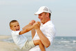Mid adult father playing with little son on beach