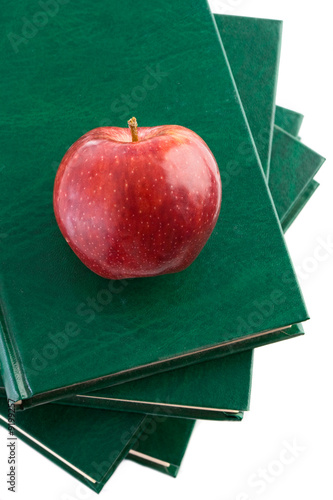 Photo: A red apple red on a green book on a white background A red apple red on a green book on a white background