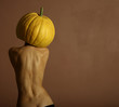 Sexy lady with big pumpkin on head. Surrealstic portrait.