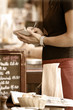 Toned outdoor cafe scene with waitress taking order