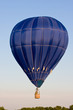 Colorful blue hot air balloon at festival mid-air on a clear day