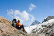 Man with backpack sitting on rock in high mountains