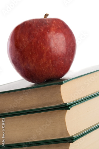 Photo: A red apple on top of books on a white background A red apple on top of books on a white background