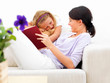 Foto: Young mother with her daughter holding book at home Young mother with her daughter holding book at home