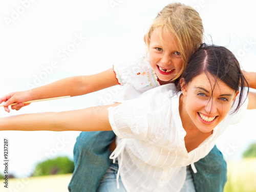 Foto: Portrait of young mother piggybacking her daughter Portrait of young mother piggybacking her daughter