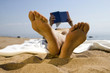 Foto: Woman lying on beach, reading book (focus on foreground) Woman lying on beach, reading book (focus on foreground)