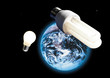 Energy saving lamp and electric bulb, image of earth in space in background, (digital composite)